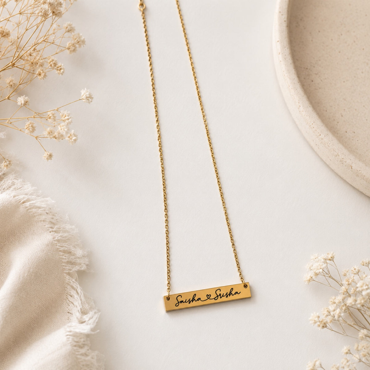 Gold personalized bar necklace engraved with names Saisha and Susha on white background with baby's breath flowers - custom name bar necklace by RA Kreations