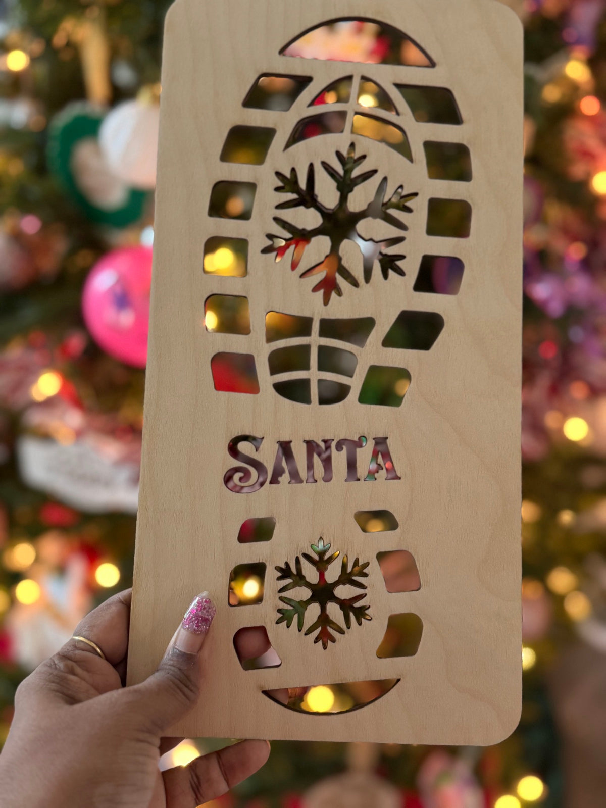 Close-up of wooden Santa footprint stencil with SANTA lettering and snowflake designs