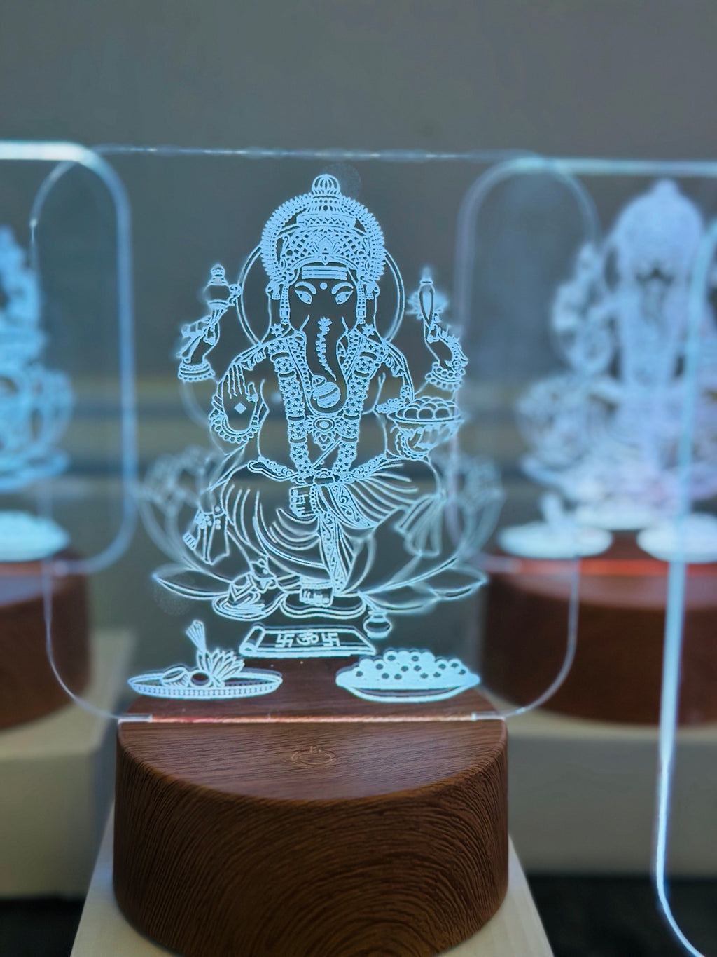 Close-up of Lord Ganesha 3D LED night light with engraved modak bowl and pooja offerings on wooden base