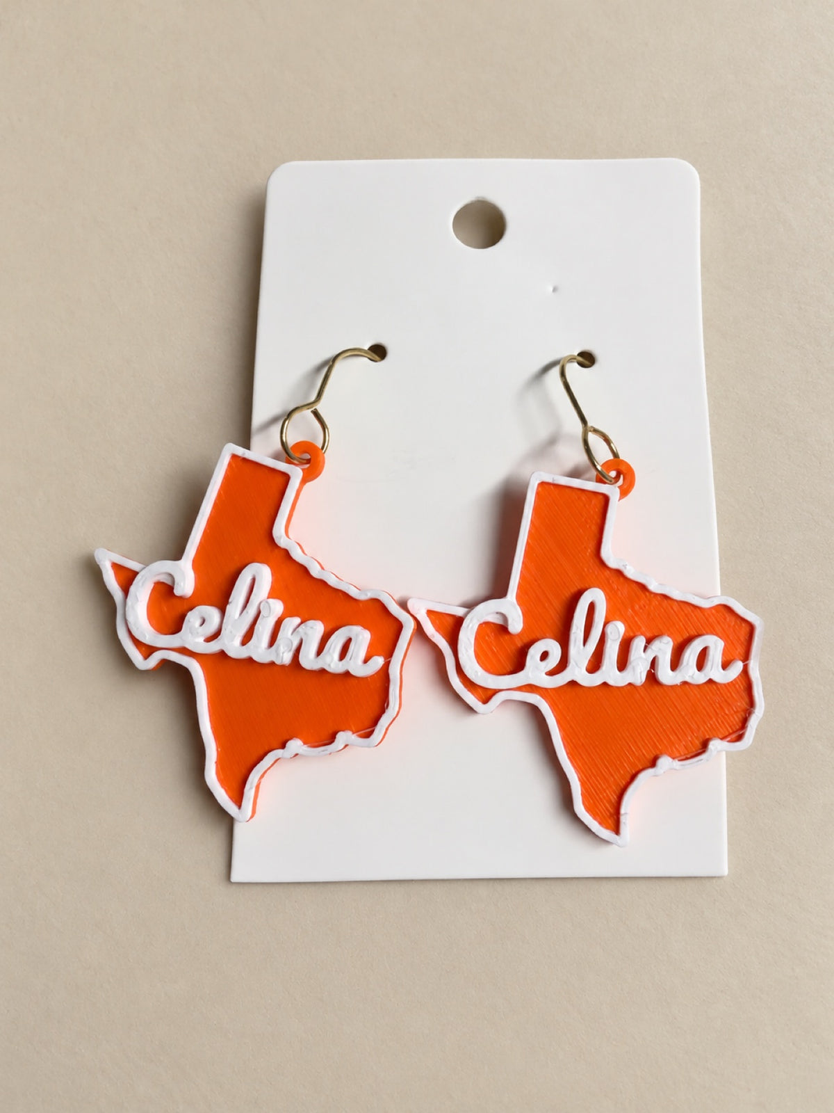 3D printed Texas state dangle earrings with Celina script in orange and white - hometown game day jewelry