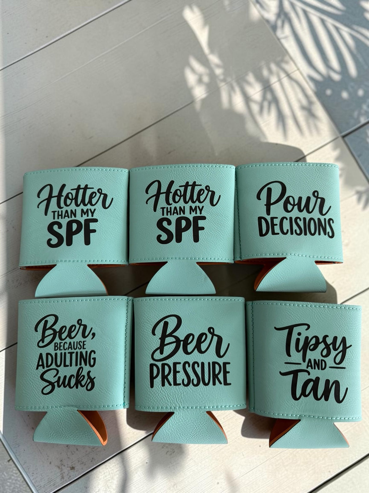Custom leatherette can coolers in mint teal with funny beer sayings engraved in black