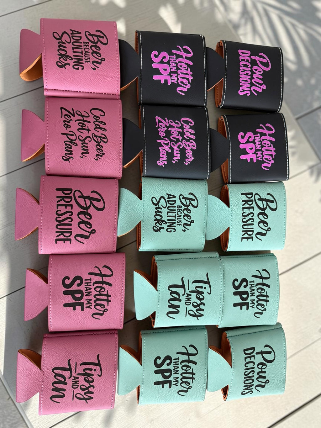 Leatherette can coolers in pink, black, and mint with funny beer sayings