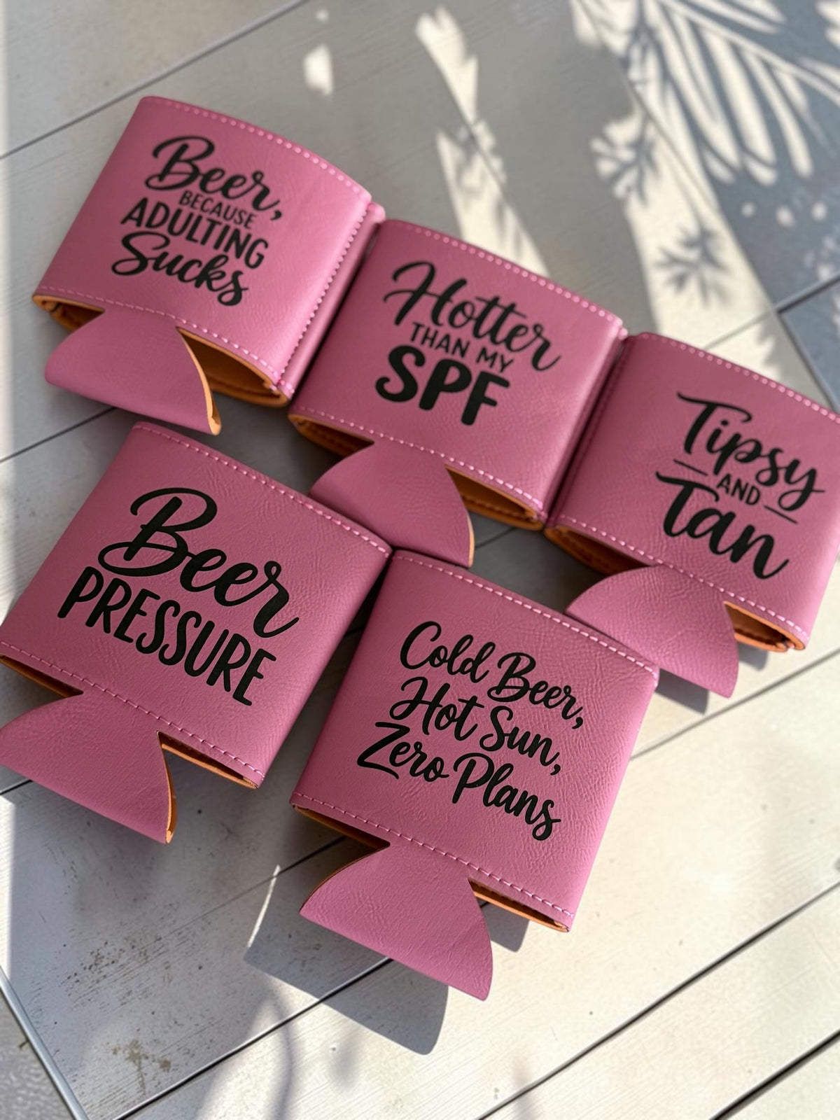 Pink leatherette can coolers with funny beer sayings engraved in black