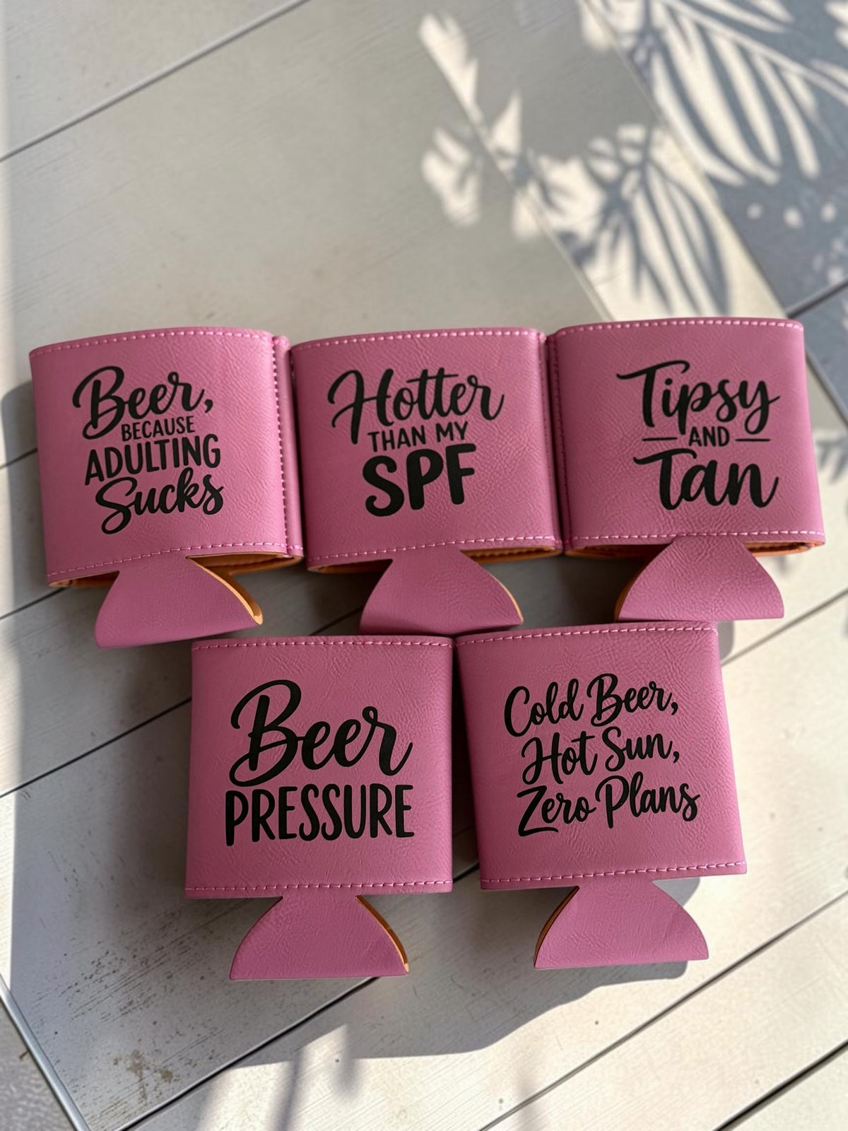 Pink leatherette can coolers with funny beer sayings engraved in black