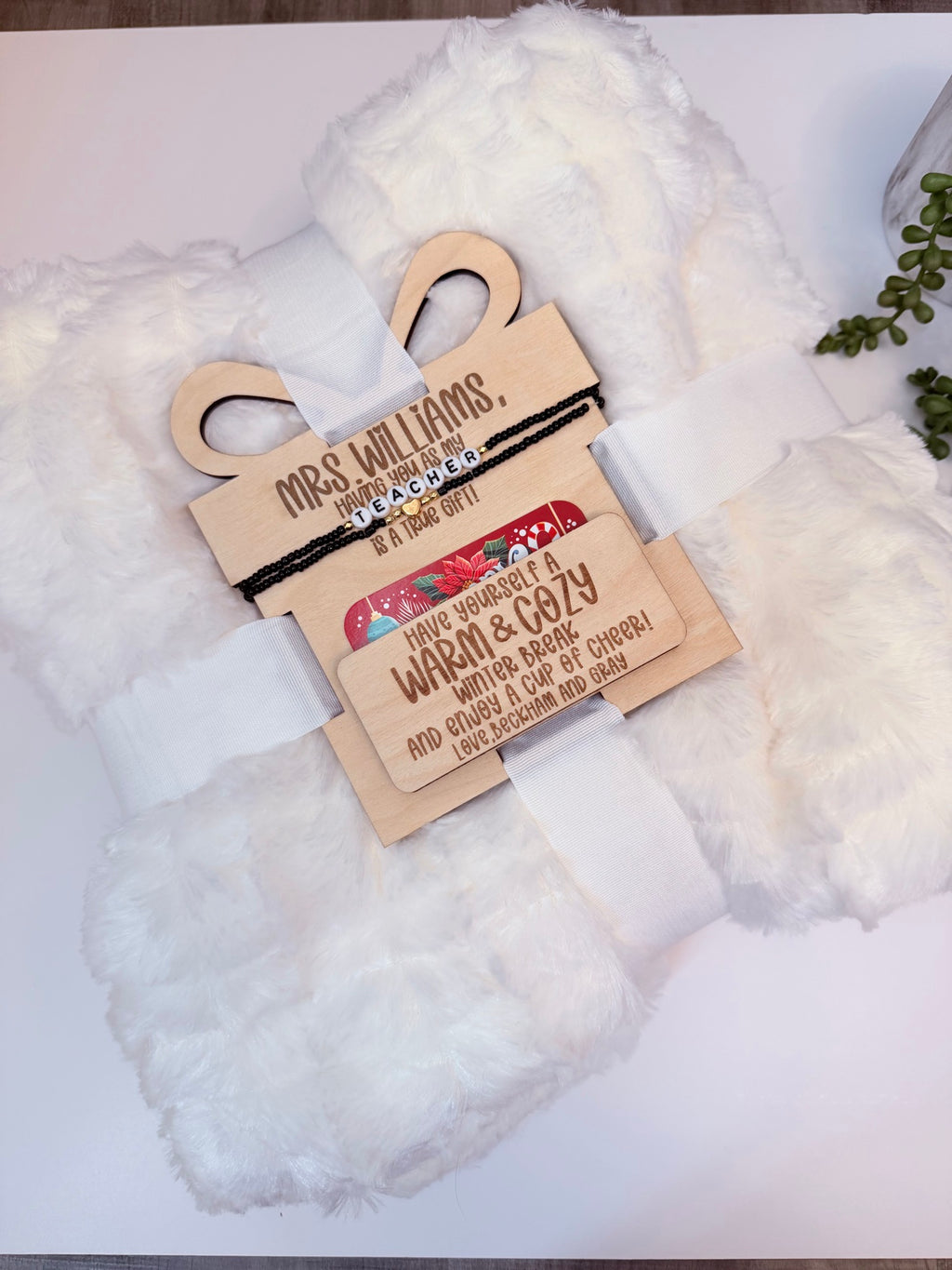 Personalized teacher Christmas gift set with white fuzzy blanket, engraved wooden gift tag and teacher bracelet