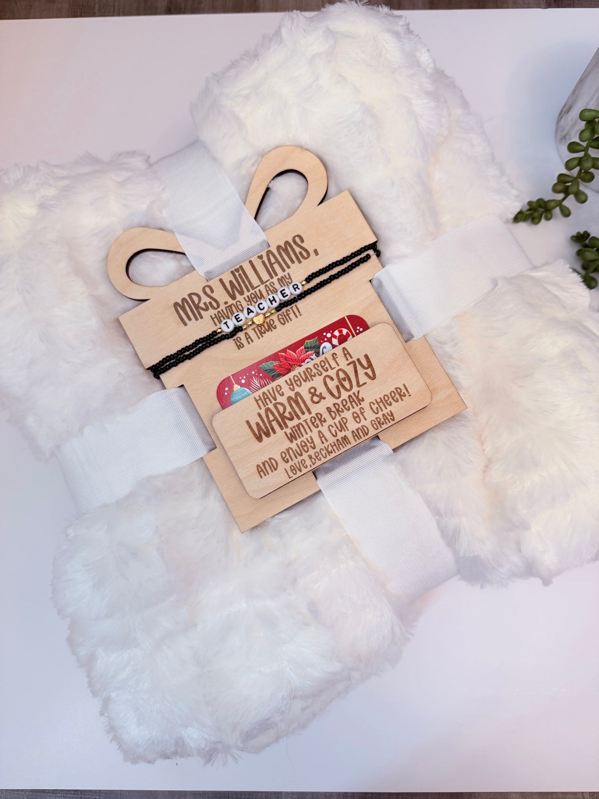 Personalized teacher Christmas gift set with white fuzzy blanket, engraved wooden gift tag and teacher bracelet