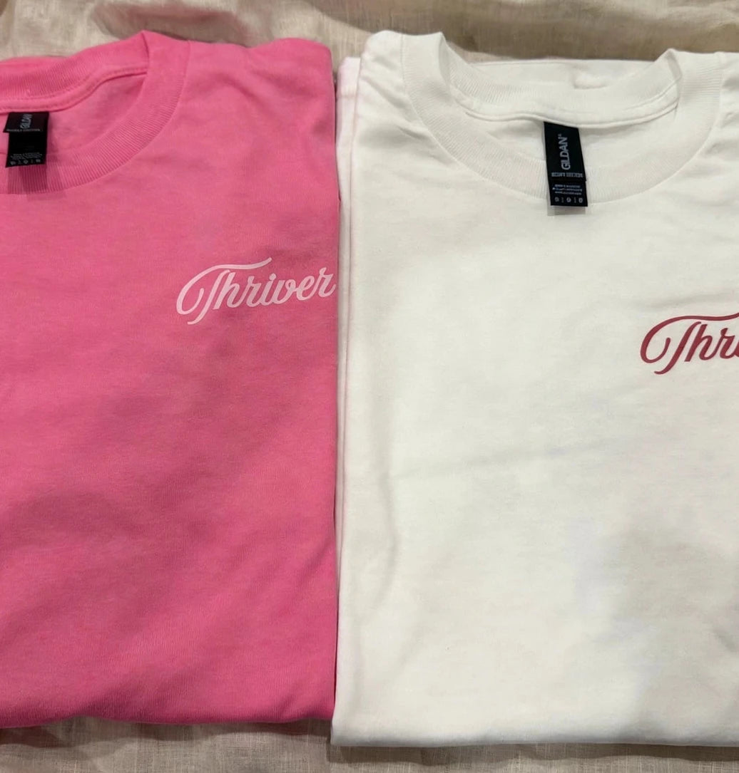 Folded custom pink and white DTF t-shirts with personalized Thriver chest script