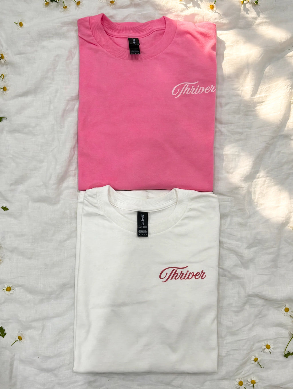 Custom pink and white DTF t-shirts with personalized chest text, lifestyle flat lay