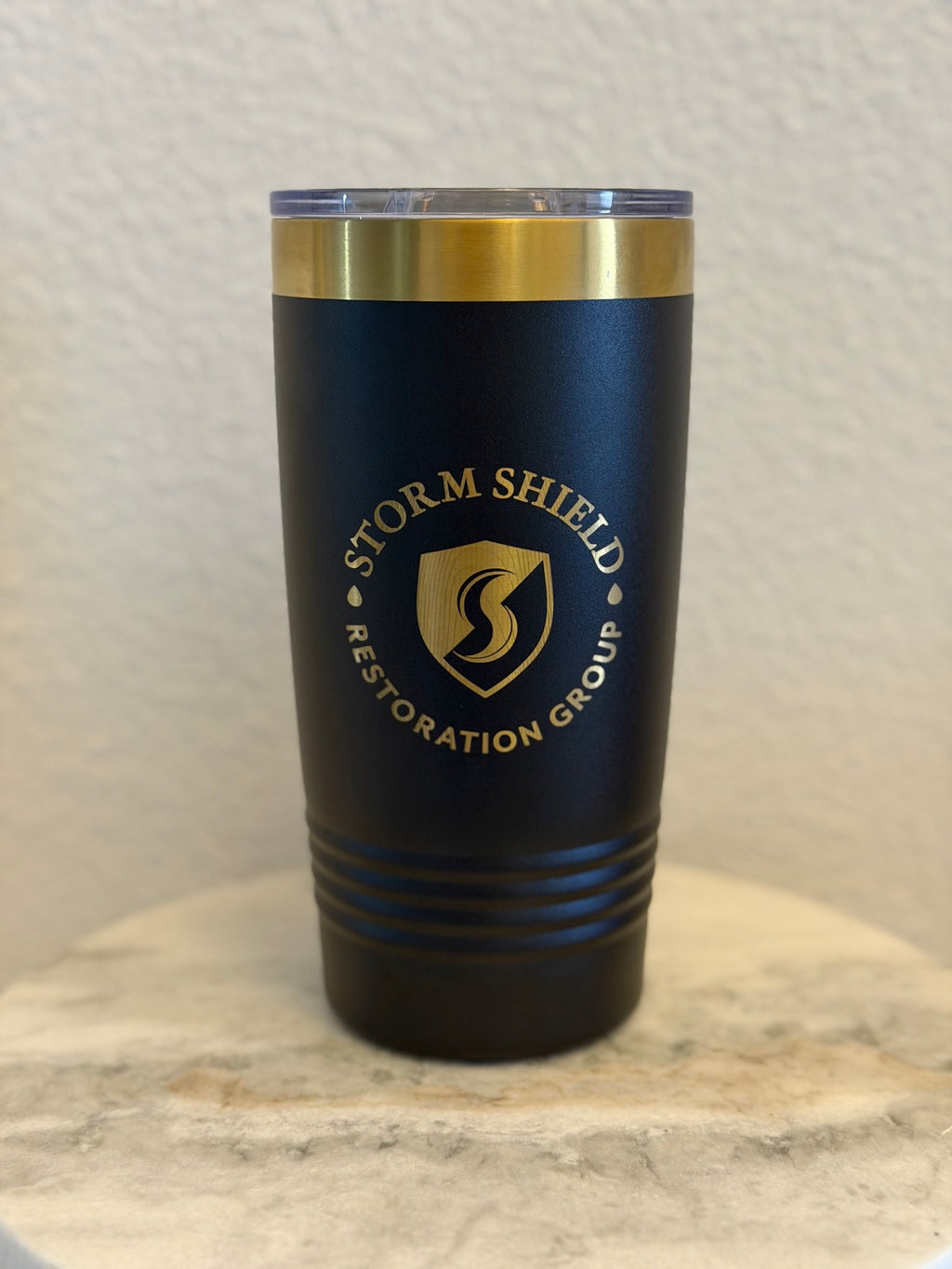 Custom black 20oz tumbler with gold laser-engraved Storm Shield Restoration Group business logo